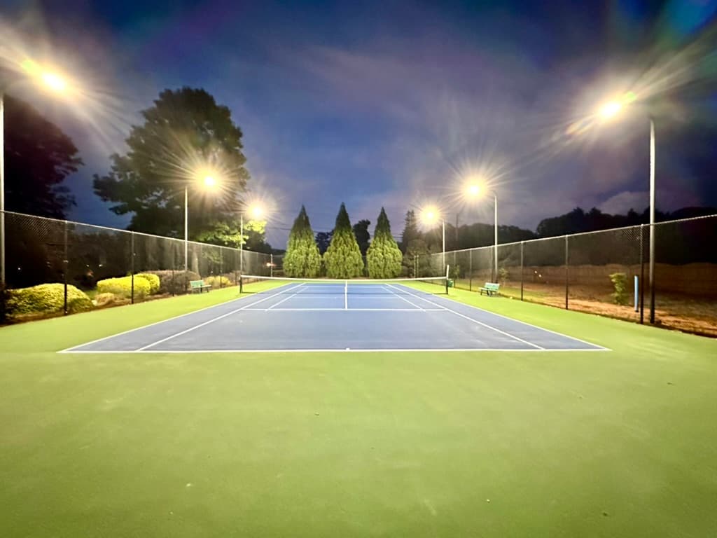 Tennis court with full LED pole lighting at dusk
